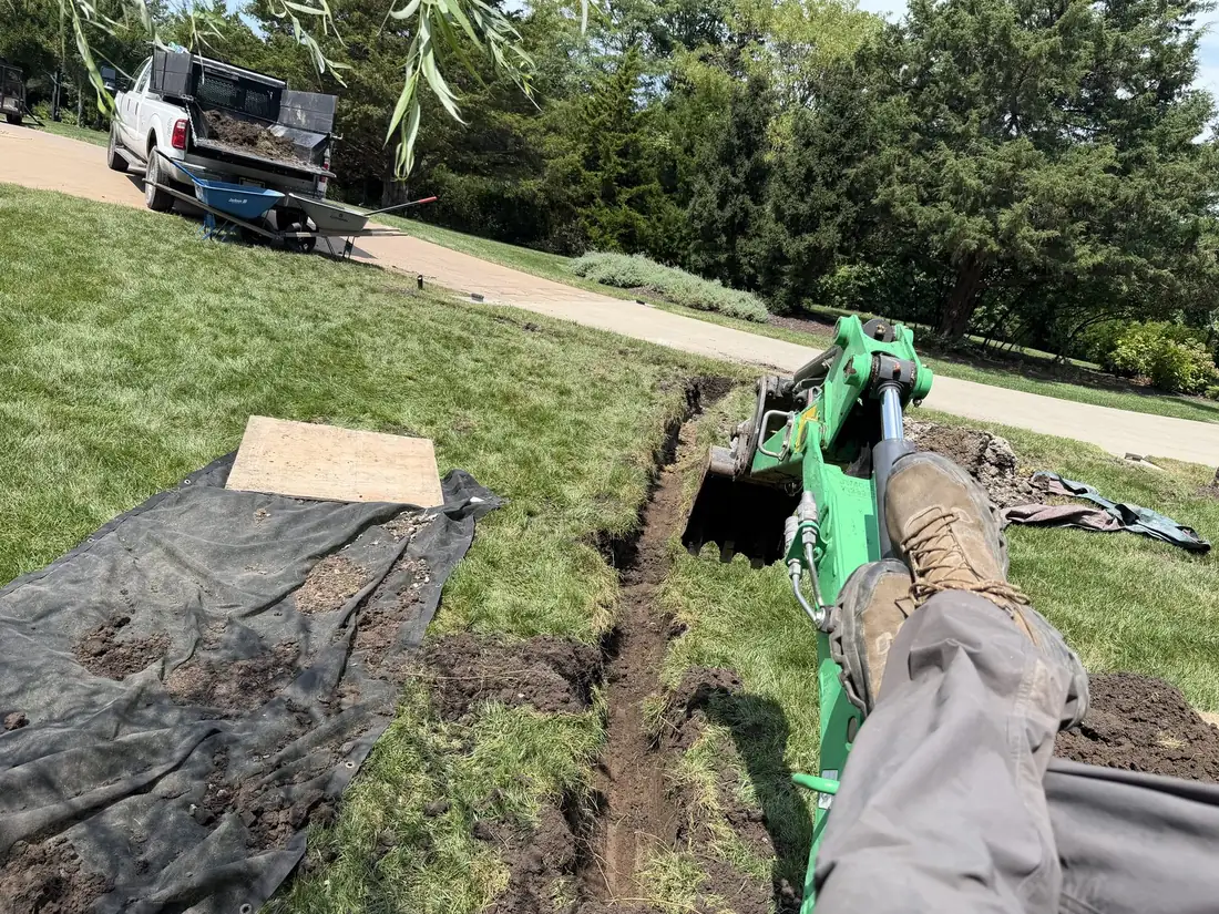 Mission Drainage crew trenching a French drain line with a mini excavator